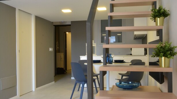 Een modern interieur met een trap, een eethoek en een keuken.