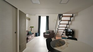 Een moderne woonkamer met een bank, een eettafel en een trap.