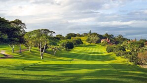 A golf course with well-manicured fairways, sand bunkers, and a clubhouse in the background. - San Lameer Villa Rentals 3005 (Southbroom)