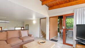 A living room with a beige sofa, a wooden coffee table, a television, and a sliding glass door leading to an outdoor area. - San Lameer Villa Rentals 3005 (Southbroom)