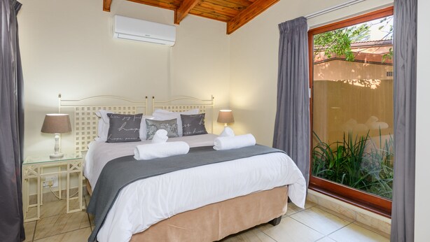 A bedroom with a bed, bedside tables, a window with curtains, and an air conditioning unit. - San Lameer Villa Rentals 3005 (Southbroom)