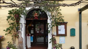 An entrance with a wooden archway, a door, and a small window with a sign. - Locanda San Gallo (Moggio Udinese)