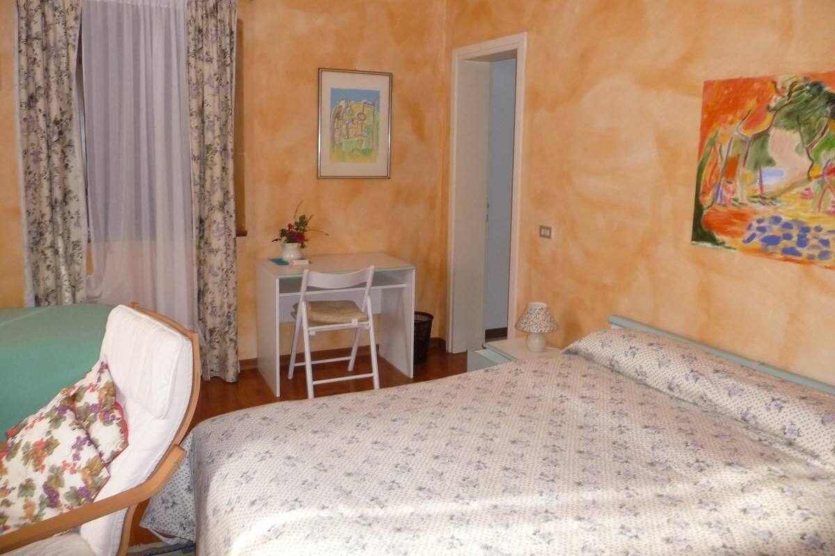 Une chambre à coucher avec un lit, un bureau, une chaise et un tableau au mur.