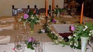A table set for a meal with wine glasses, a vase with flowers, and candles. - Locanda San Gallo (Moggio Udinese)