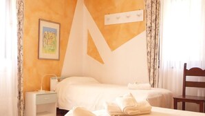 A hotel room with a bed, a nightstand, a chair, and a painting on the wall. - Locanda San Gallo (Moggio Udinese)