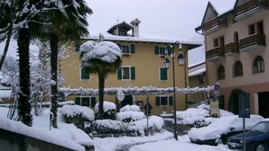A snow-covered courtyard with a pathway leading to a building with balconies. - Locanda San Gallo (Moggio Udinese)