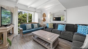 Un salon moderne avec une table basse en bois, un canapé gris et un canapé bleu agrémenté de coussins à motifs.