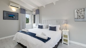 A modern bedroom with a large bed, white bedding, a bedside table with a lamp, and a framed picture on the wall. - San Lameer Villa Rentals 3108 (Southbroom)