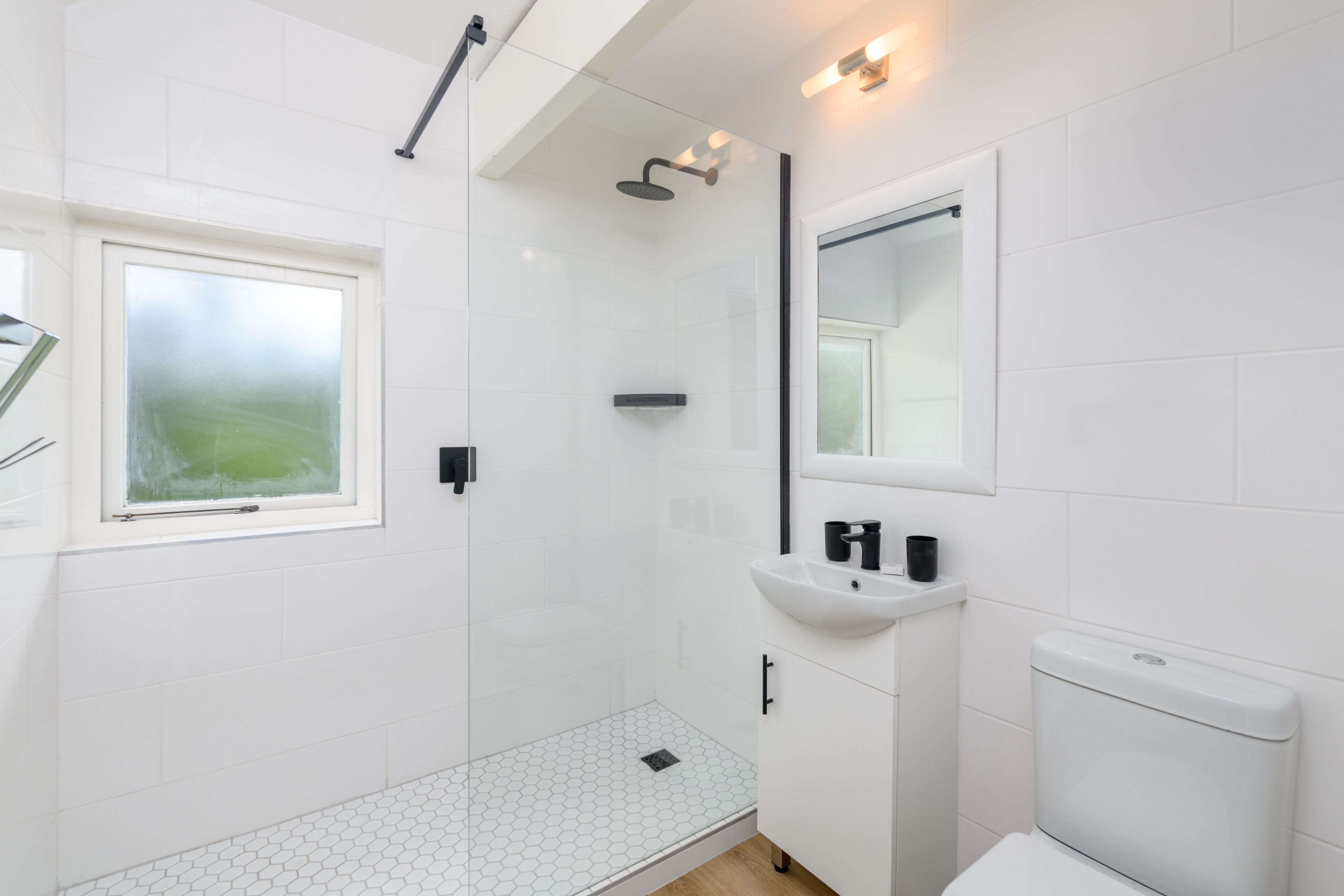 Een moderne badkamer met een douchecabine van glas, een wit wastafelmeubel en een toilet.