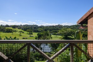 A view from a balcony overlooking a golf course with a pond, surrounded by lush greenery and a clear blue sky. - San Lameer Villa Rentals 2529 (Southbroom)