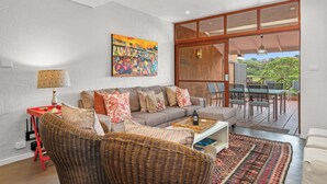 A living room with a sofa, a wicker chair, a coffee table, and a painting on the wall. - San Lameer Villa Rentals 2534 (Southbroom)