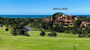 A golf course with a view of a resort complex in the background. - San Lameer Villa Rentals 2534 (Southbroom)