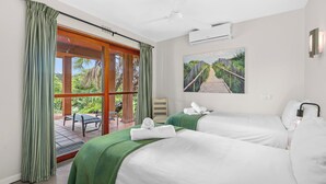 A hotel room with two beds, a large window with curtains, a ceiling fan, an air conditioning unit, a painting of a pathway, and a small table with a chair outside. - San Lameer Villa Rentals 2534 (Southbroom)