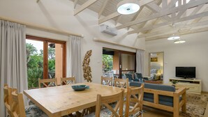 A dining area with a wooden table and chairs, a sofa, and a television in a living room. - San Lameer Villa Rentals 2702 (Southbroom)