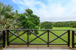 Enjoy a serene view of the well-maintained lawn and surrounding trees from this balcony.
