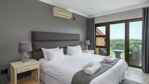 A modern hotel room with a large bed, two bedside tables, a lamp, an air conditioning unit, and a balcony with a view. - San Lameer Villa Rentals 14109 (Southbroom)