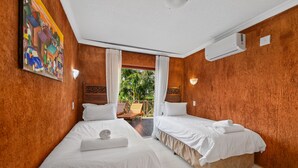 Hotellihuone, jossa on kaksi sänkyä, valkoiset vuodevaatteet, taulu seinällä ja näkymä ulos.