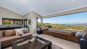 A spacious living room with a large window offering a scenic view, a sofa set, and a coffee table. - San Lameer Villa Rentals 14205 (Southbroom)