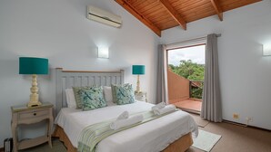 A bedroom with a bed, two bedside tables with lamps, a window with curtains, and an air conditioning unit. - San Lameer Villa Rentals 1924 (Southbroom)