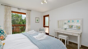 A bedroom with a bed, a desk, a chair, a window with curtains, and a view of greenery outside. - San Lameer Villa Rentals 10307 (Southbroom)