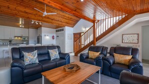 A spacious living area with a wooden ceiling, a staircase, and a kitchen in the background. - San Lameer Villa Rentals 10307 (Southbroom)
