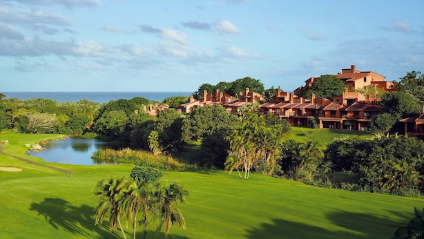 A golf course with a pond, palm trees, and a view of the ocean. - San Lameer Villa Rentals 1914 (Southbroom)