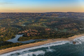 An aerial view of a coastal town with a beach, a river, and surrounding hills. - San Lameer Villa Rentals 1929 (Southbroom)