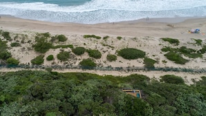 An aerial view of a beach with waves, sparse vegetation, and a fenced area. - San Lameer Villa Rentals 1929 (Southbroom)