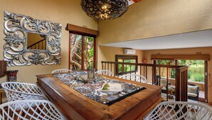 A dining area with a wooden table, white chairs, a decorative mirror, and a hanging light fixture. - San Lameer Villa Rentals 3506 (Southbroom)