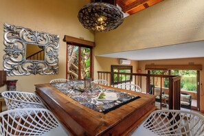A dining area with a wooden table, white chairs, a decorative mirror, and a hanging light fixture. - San Lameer Villa Rentals 3506 (Southbroom)