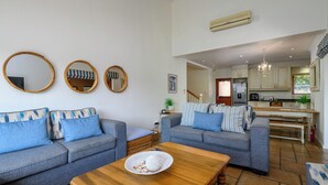 A living room with two grey sofas, a wooden coffee table, and three round mirrors on the wall. - San Lameer Villa Rentals 10432 (Southbroom)