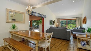 A spacious living area with a dining table, sofas, and a view of a golf course. - San Lameer Villa Rentals 10432 (Southbroom)