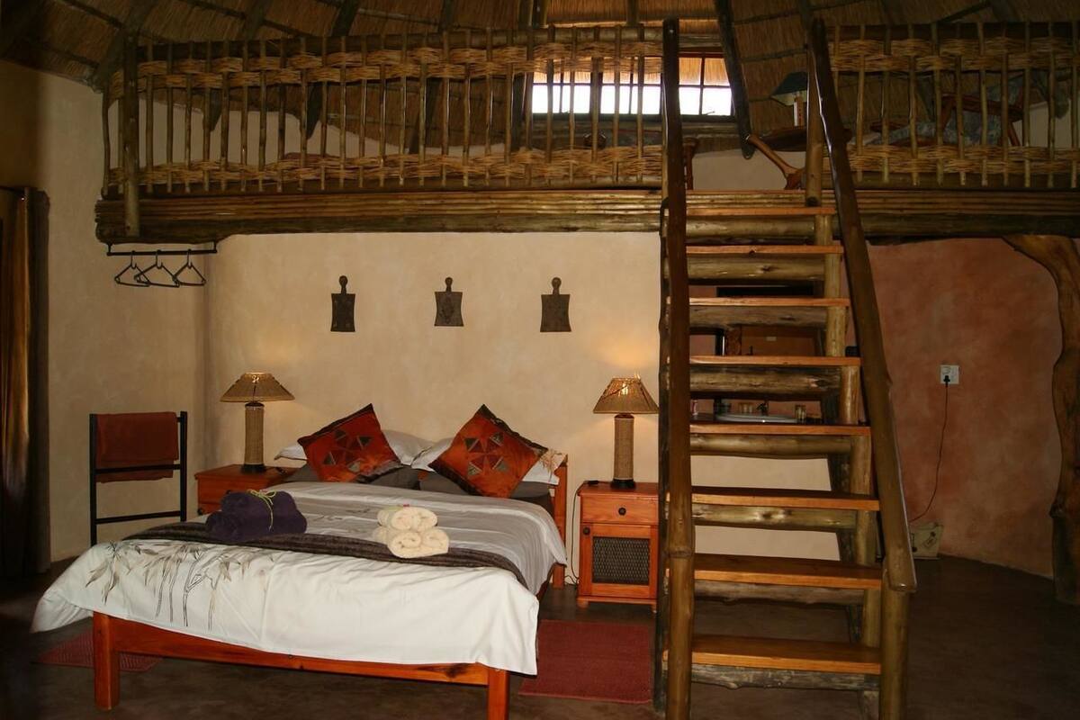 A rustic room with a wooden bed, two nightstands, a ladder, and a woven ceiling.