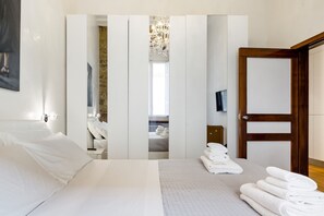 A modern hotel room with a large bed, a wooden door, and a view of a bathroom through a frosted glass partition. - Luxury 2 Bedroom Apartment with Hot Tub - Florence City Center (Florence)