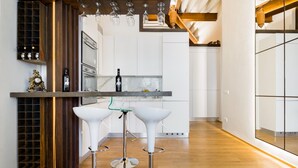 A modern kitchen with white cabinets, a wine rack, and two white bar stools. - Luxury 2 Bedroom Apartment with Hot Tub - Florence City Center (Florence)
