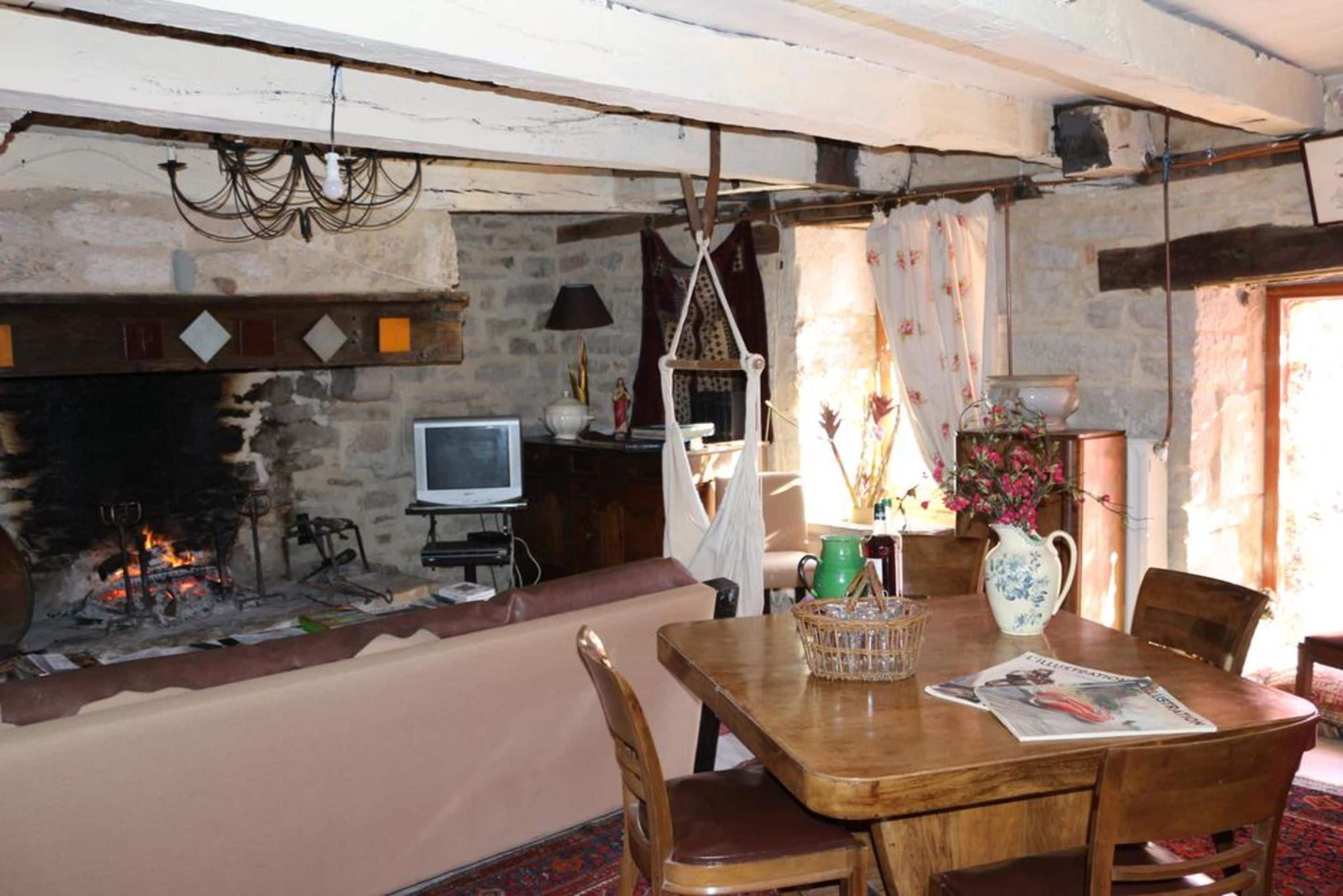 A rustic room with a stone fireplace, wooden furniture, and a television.