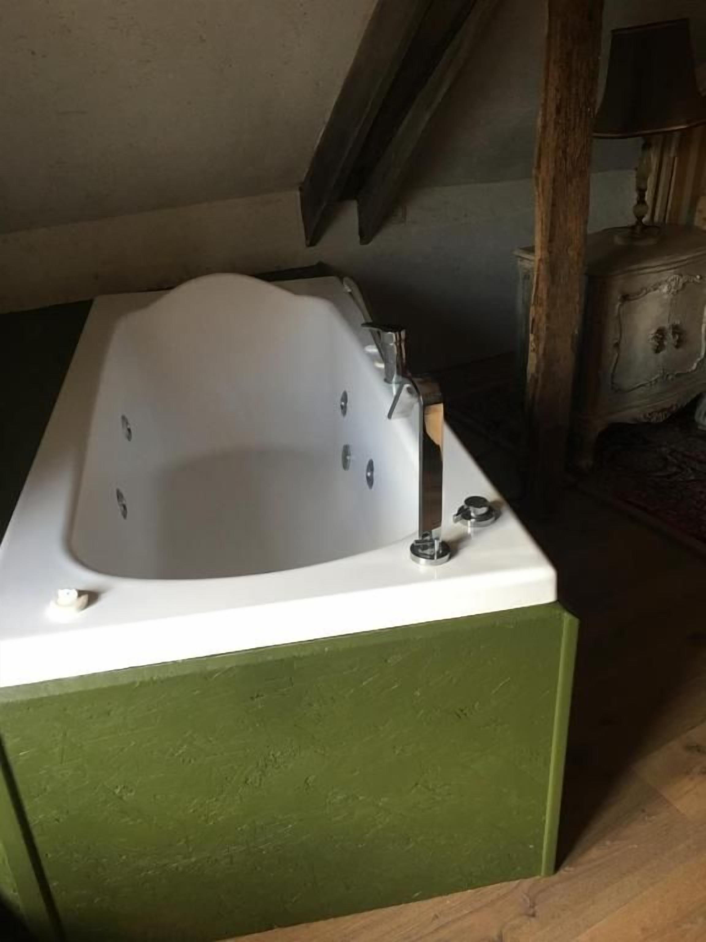 A bathroom with a bathtub, a faucet, and a wooden cabinet.
