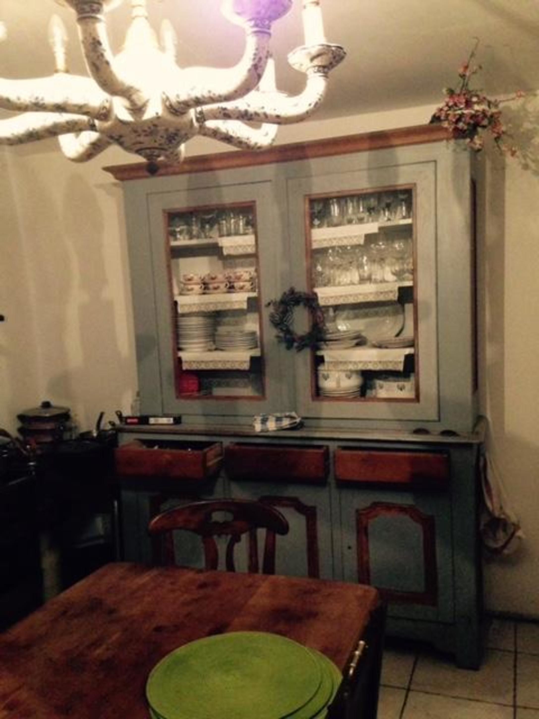Una cocina con armarios de madera, una lámpara de araña y una mesa de comedor con sillas.