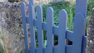 A blue wooden fence with a stone wall in the background.