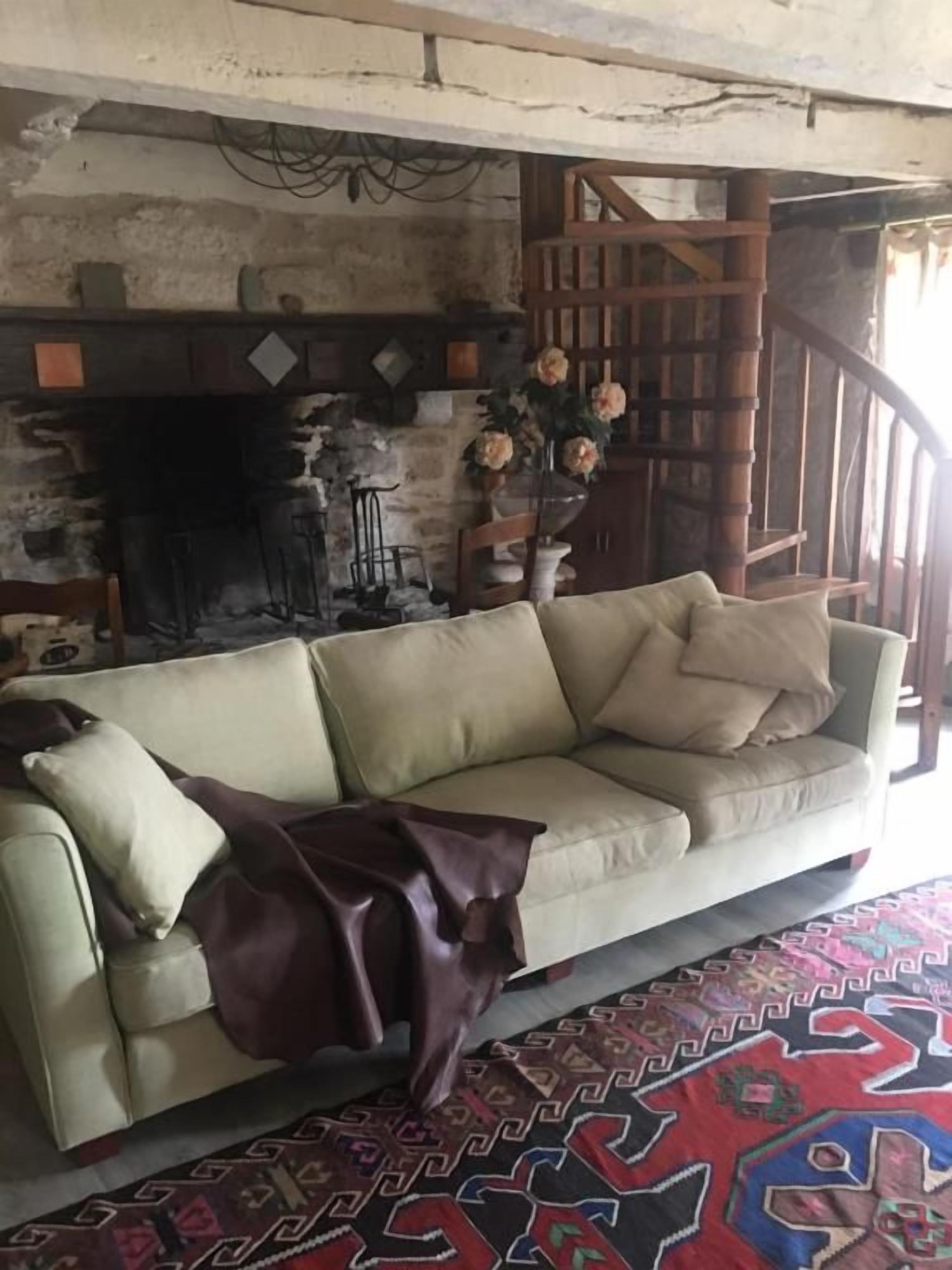 A living room with a sofa, a patterned rug, a fireplace, and a staircase.