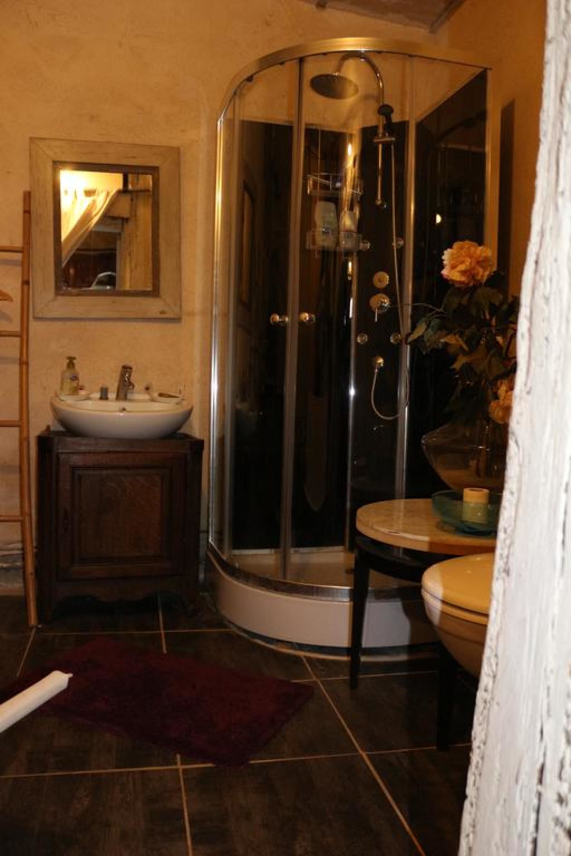 A bathroom with a glass-enclosed shower, a sink, and a mirror.