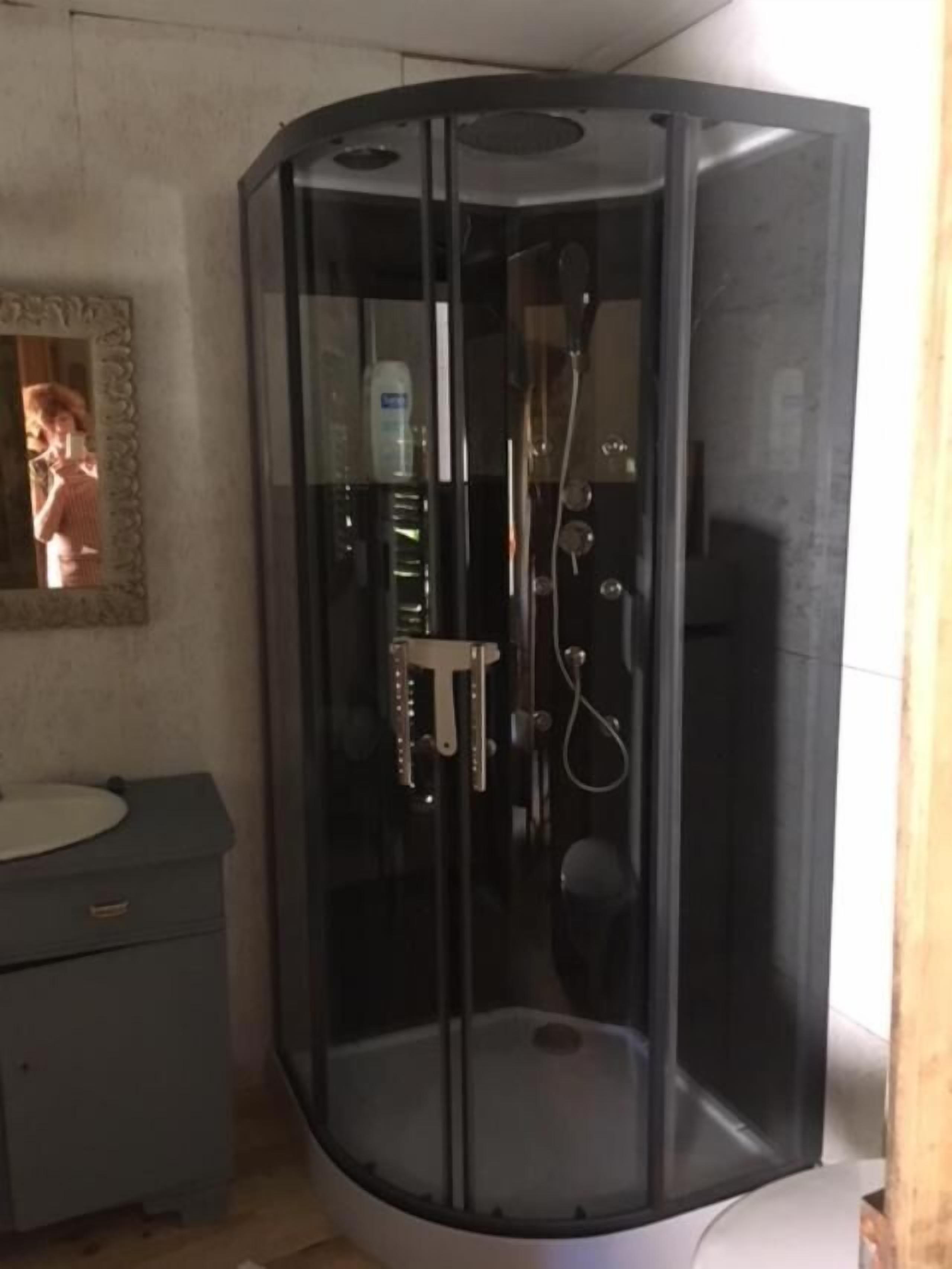 A bathroom with a glass-enclosed shower, a sink, and a mirror.
