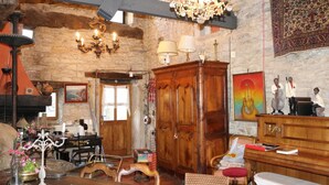 A rustic room with a wooden cabinet, a chandelier, and a large tapestry on the wall. - Le Moulin à Huile (Vailhourles)