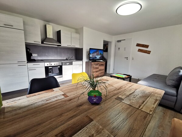 A modern kitchen with white cabinets, a built-in oven, and a TV on the wall. - Speedys Gästehaus am Brünnchen (Herresbach)