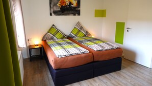 A double bed with striped bedding, a nightstand with a lamp, and a painting of a fox on the wall. - Speedys Gästehaus am Brünnchen (Herresbach)