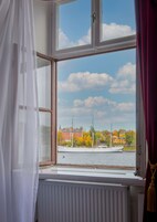 Habitación con un ventanal grande con vistas a un río, un radiador blanco y una cortina.