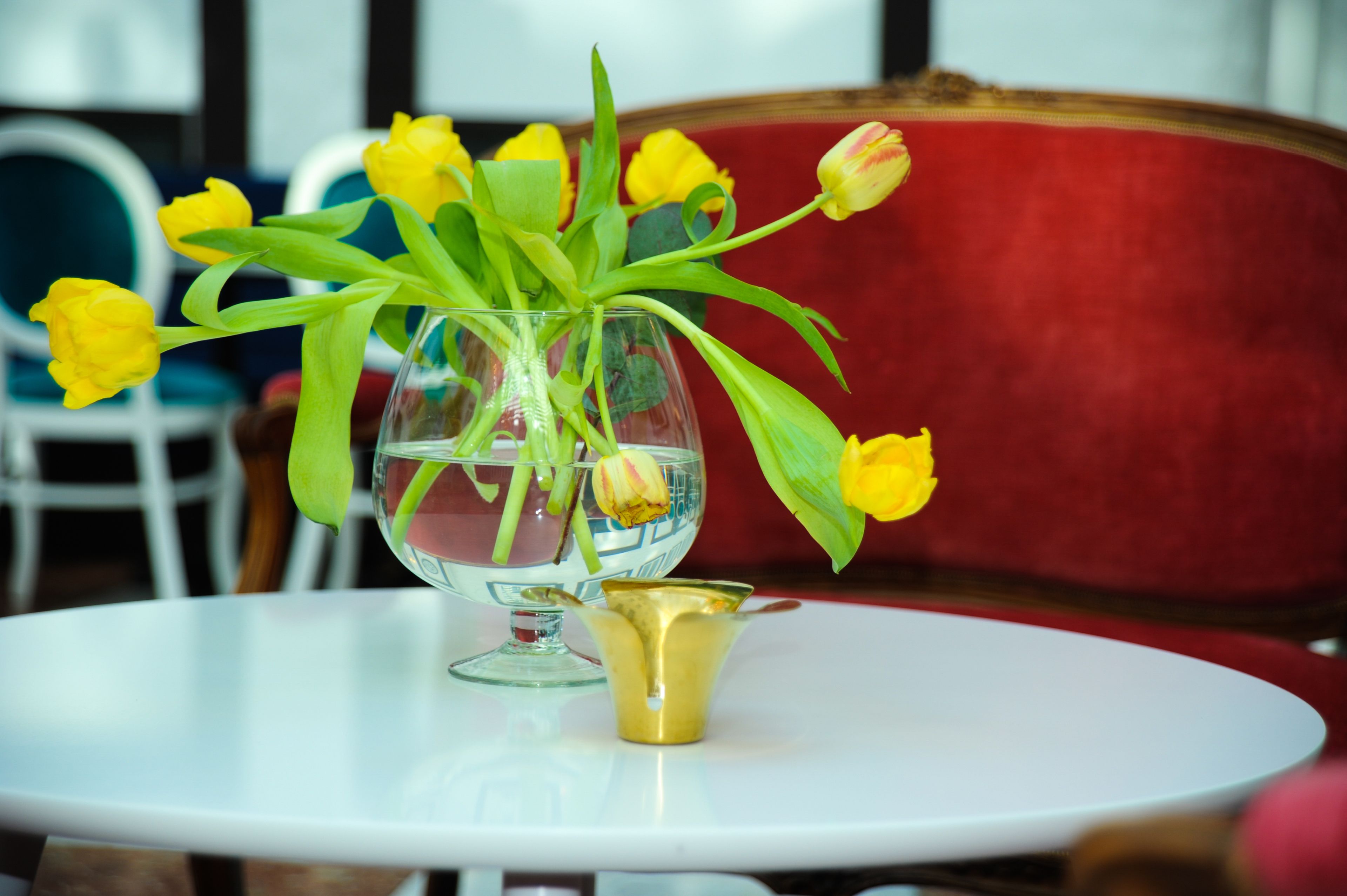 A glass vase with yellow tulips on a white table.