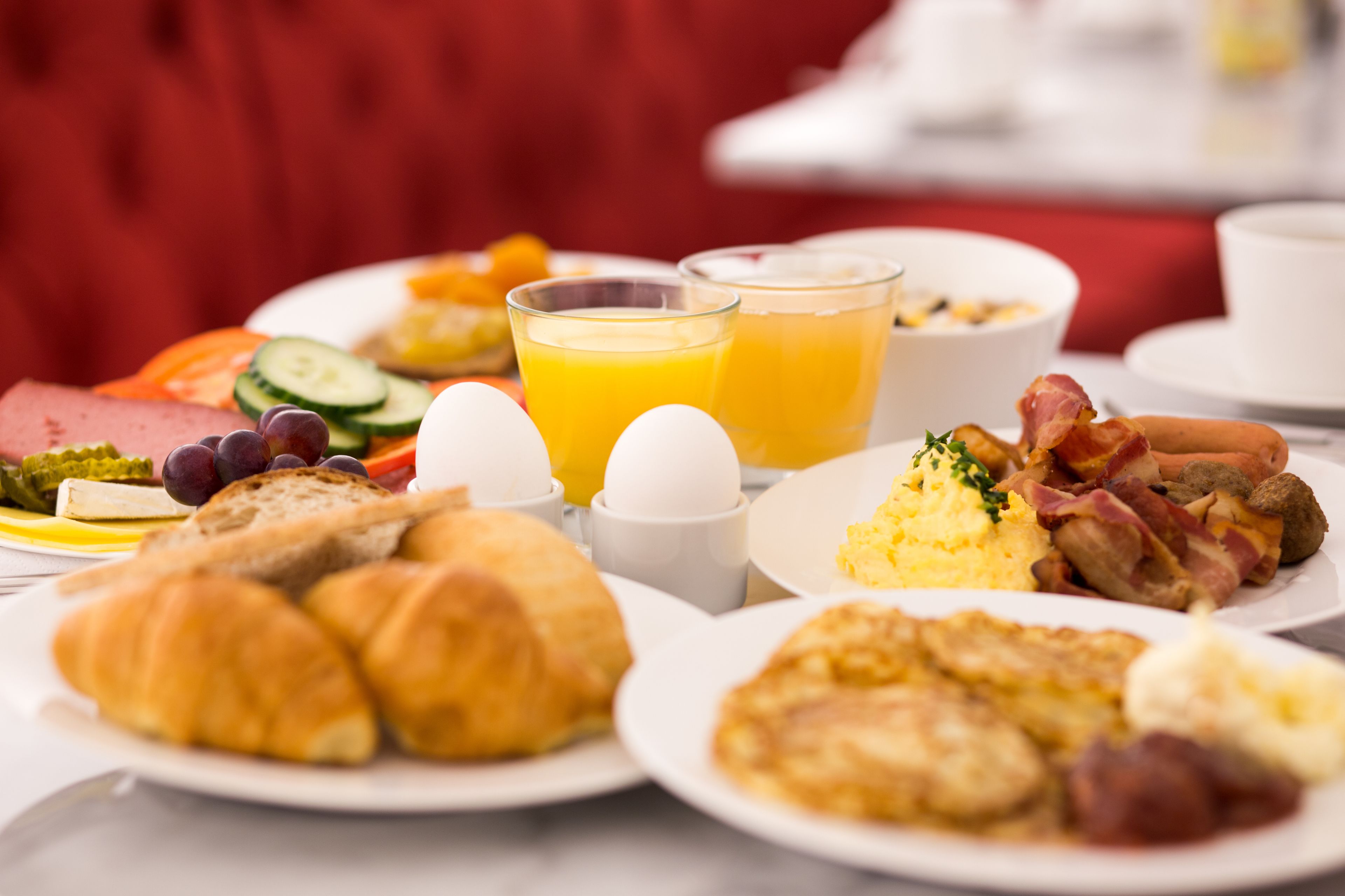 Una mesa de desayuno con diversos platos, incluyendo huevos, tocino y bollería.
