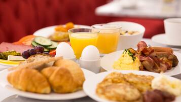 Una mesa de desayuno con diversos platos, incluyendo huevos, tocino y bollería.