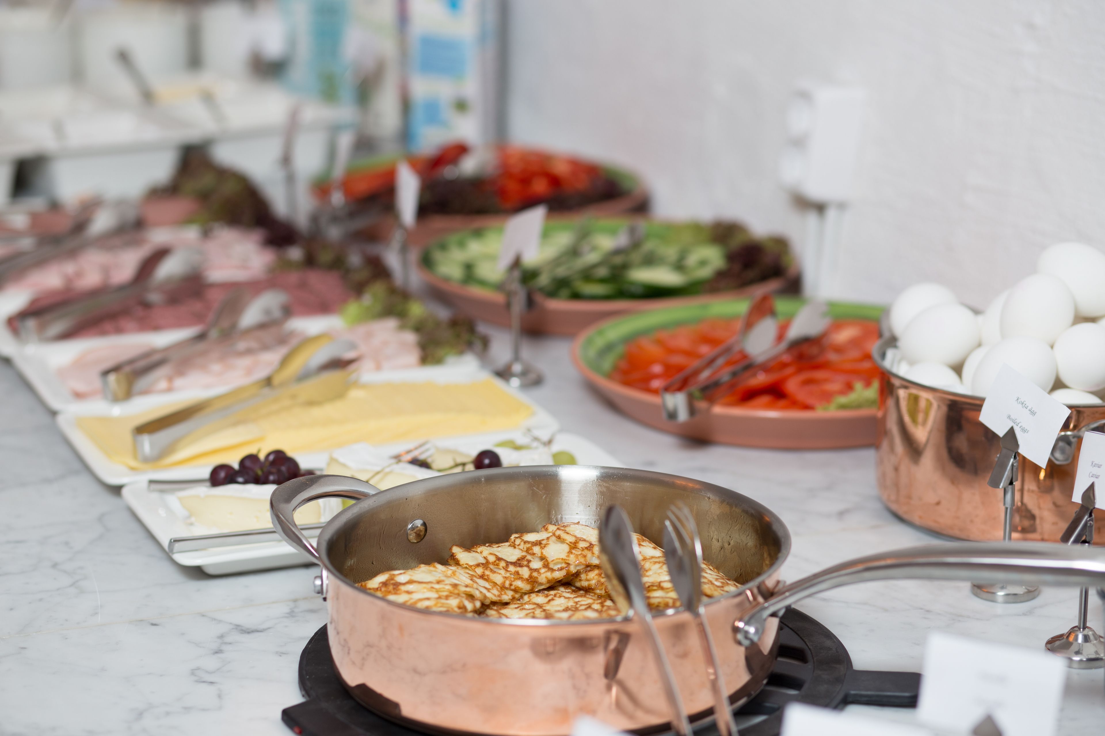 A buffet with various food items including meats, cheeses, and vegetables.